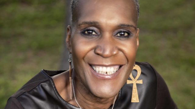 Andrea Jenkins, Minneapolis City Council President, smiles while seated on a bench