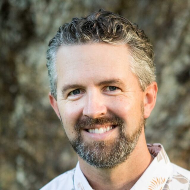 Capt. Chris Marvin is a retired member of the U.S. Army. He is a white male with short grey-and-brown hair, a beard and mustache, and is wearing a white collared shirt.