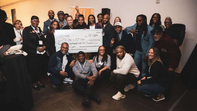 A group of grantees pose with Community Safety Fund team members for a photo. Several people are holding a large check that reads: 