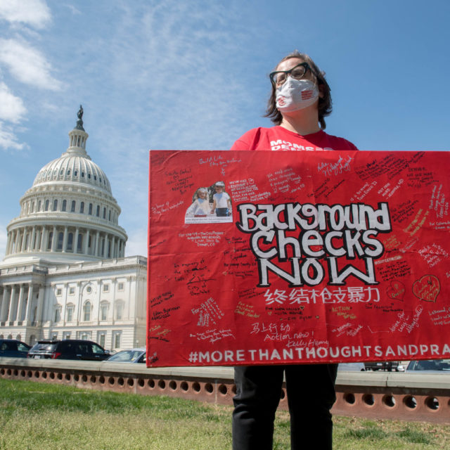 Masked Moms Demand Action volunteer holding a red 
