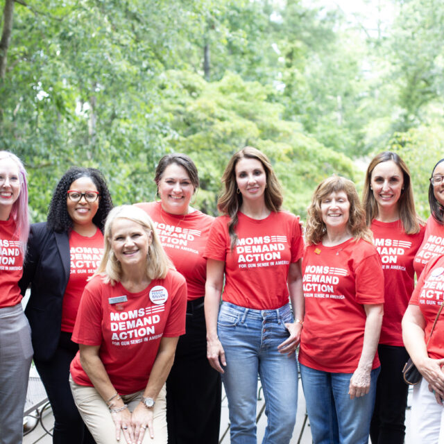 Moms Demand Action volunteers pose in red Moms Demand Action t-shirts alongside founder Shannon Watts