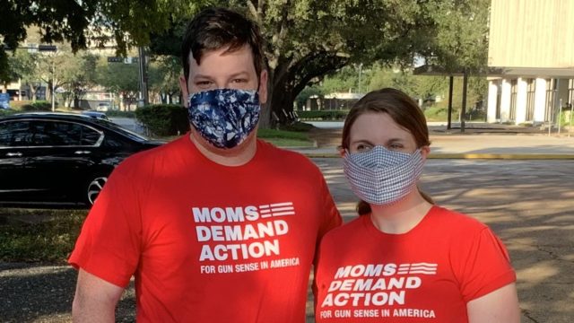 Moms Demand Action volunteer Claire Hein Blanton poses for a photo next to her husband. They are both masked and wearing red Moms Demand Action t-shirts.