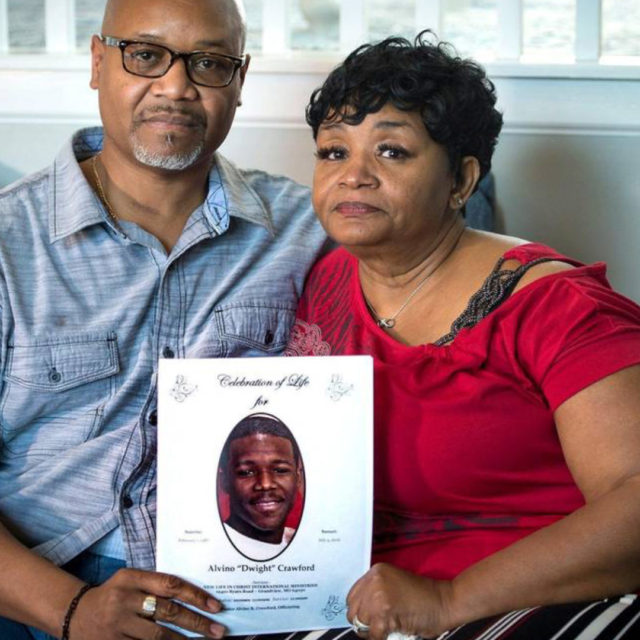 Alvino and Beverly Crawford hold up a sign of their son