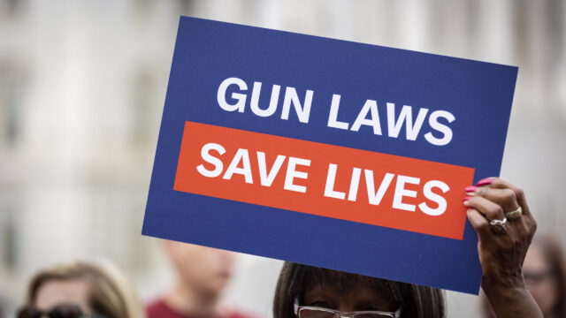 A volunteer holds a “Gun Laws Save Lives” sign