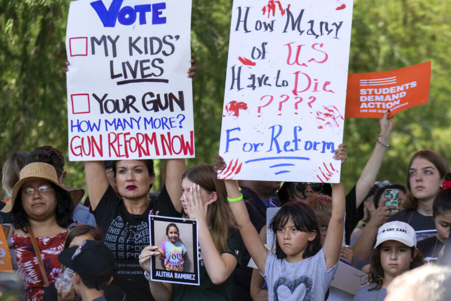 Protesters hold up signs outside the NRA Convention