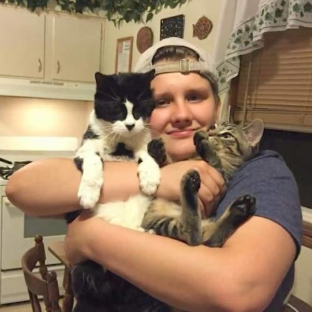 Haven Bailey, a white trans man, smiles while holding a cat