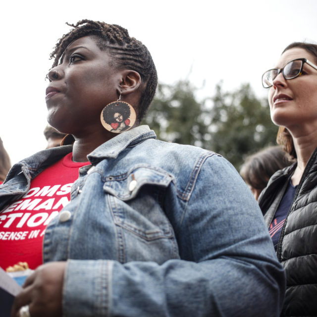 A woman wearing a Moms Demand Action shirt in a crowd at an event