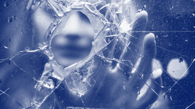 A blurred face and hand are visible in the background of the image, behind the foreground of splintered glass. In the center, there is a bullet hole through which the person's face is visible. The person appears to be reaching out toward the viewer. The image is meant to reflect how lives can be shattered by intimate partner homicide-suicide.